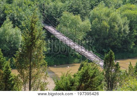 Suspended wooden bridge across Schodnica river in Carpathians Ukraine