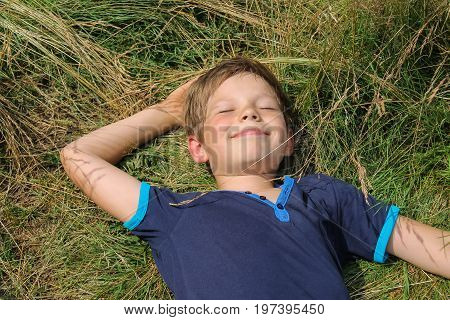 Handsome boy lying on suumer meadow grass