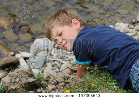 Boy lies near mountain river in Carpathians Ukraine