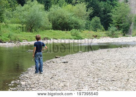 Boy near mountain river in Carpathians Ukraine