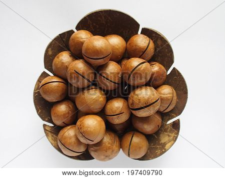 macadamia in utensil made from coconut shell on white background