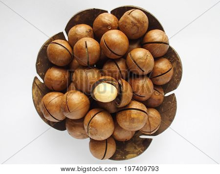 macadamia in utensil made from coconut shell on white background