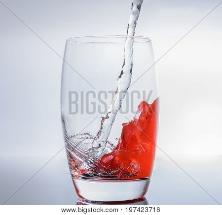 Filling water in glass with red colors for apero