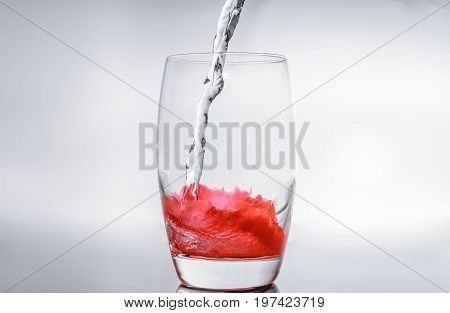 Filling water in glass with red fluid for apero