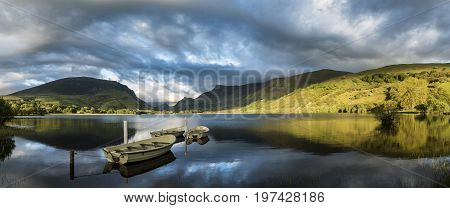 Stunning Panorama Lake Landscape With Rowing Boats In Foreground And Mountain Range In Background