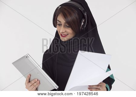 Arabic student wearing abaya holding White paper and tablet