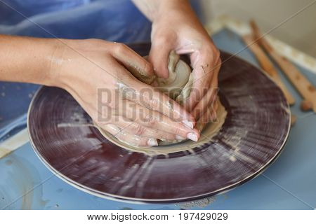 Creating a jar or vase of clay. Woman hands on potter's wheel