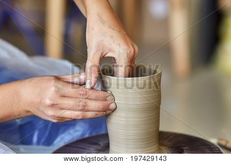 Creating a jar or vase of clay. Woman hands on potter's wheel