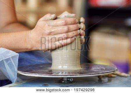 Creating a jar or vase of clay. Woman hands on potter's wheel