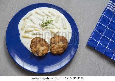 Rissole on the blue plate with young beans and cream sauce