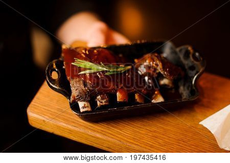 Baked pork ribs glazed in soy sauce and honey in a frying pan, close-up