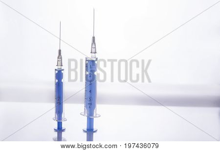 Two injections with needles stand up on white background