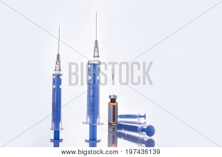 Two shots stand up and two injections laying on the white table