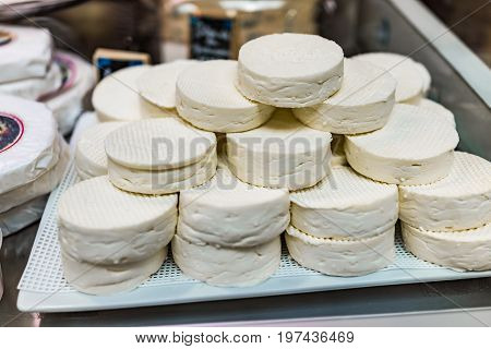 Macro Closeup Of Many Soft Cheese Rounds Pile On Display In Store