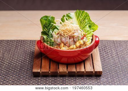 Fresh salad with lupini beans and raw fish served with lettuce leaf in bowl on table napkin