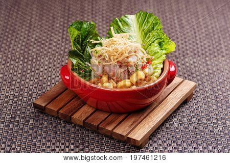 Fresh salad with lupini beans and raw fish served with lettuce leaf in bowl on table napkin