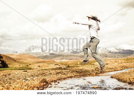 View on Girl jumping over mountain creek in China