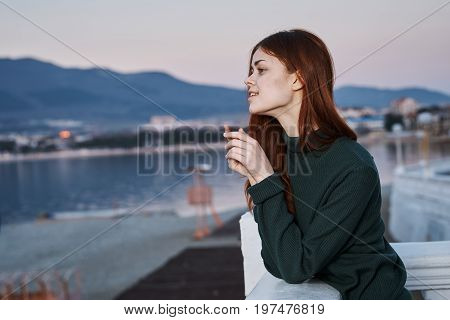 Young beautiful woman is walking in a sweater along the waterfront.