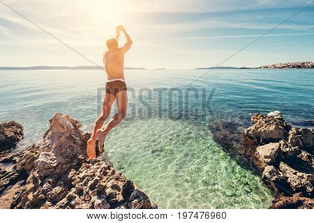 Man jumps in clear crystal water on Adriatic Sea Bay