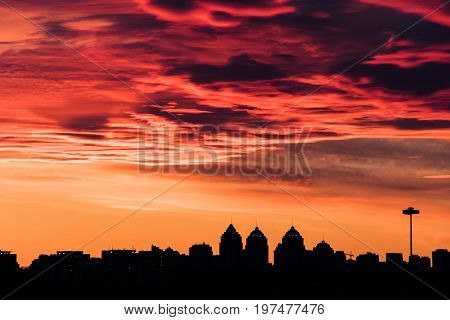colorful fiery sky at sundown with altocumulus clouds over the city skyline