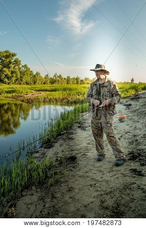 The fisherman catches a pike for spinning off the bank of the channel