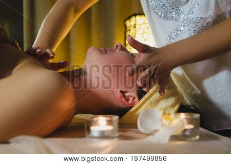 Woman having face massage treatment in wellness center.