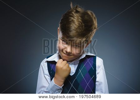 Portrait of angry boy isolated on gray background. He raised his fist to strike.