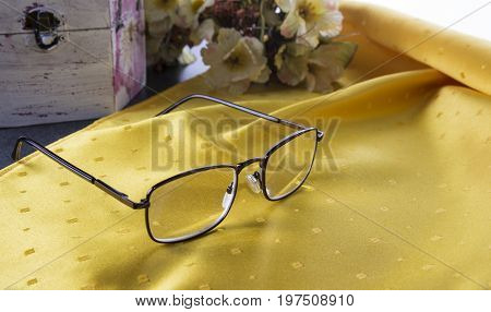 Metal frame diopter glasses on the table with flowers and old box