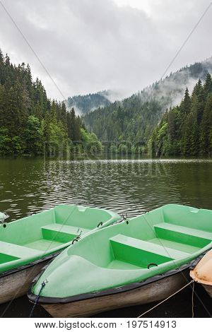 Mountain lake scenery Lacu Rosu or Red lake with boats near the shore Eastern Carpathians Romania nature landscape background.