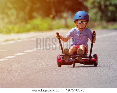 Happy boy standing on hoverboard or gyroscooter with kart accessory kit outdoor. New modern technologies