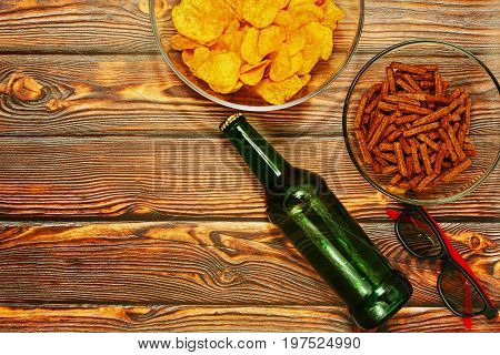 Ready to home party concept - bottle of beer and salted snacks on wooden table in rural style