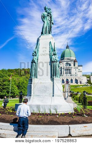 Montreal Canada - May 28 2017: St Joseph's Oratory on Mont Royal with man praying by statue in Quebec region city