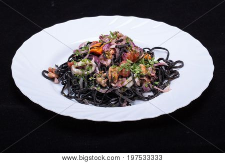 Black spaghetti with seafood and vegetables .
