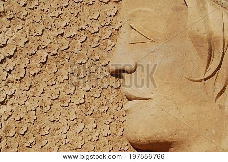 Sand Sculpture of a Woman and flowers in the background