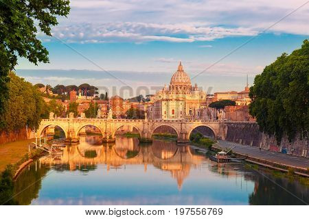 Saint Angel bridge and Saint Peter Cathedral with a mirror reflection in the Tiber River in the sunny morning in Rome, Italy.