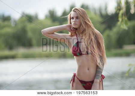 Sexy tattooed woman in lingerie in a river water.Sexy young woman relaxing on the beach.