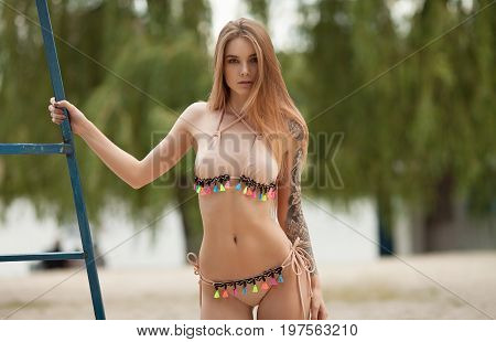 Sexy tattooed woman in lingerie in a river water.Sexy young woman relaxing on the beach.