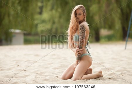 Sexy tattooed woman in lingerie in a river water.Sexy young woman relaxing on the beach.