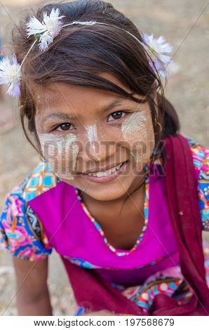MANDALAY MYANMAR - MARCH 12 : Unidentified Burmese girl with traditional thanaka on her face on March 12 2016 in Mandalay Myanmar.Thanaka is a yellowish-white cosmetic paste made from ground bark