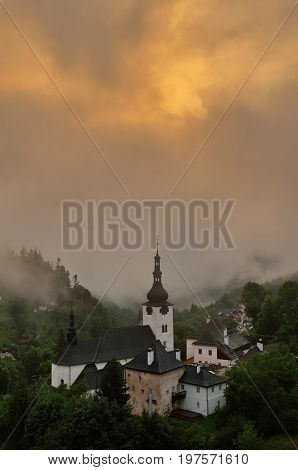 Summer in Slovakia. Old mining village. Historic church in Spania dolina. Summertime colored country in fog after the storm.