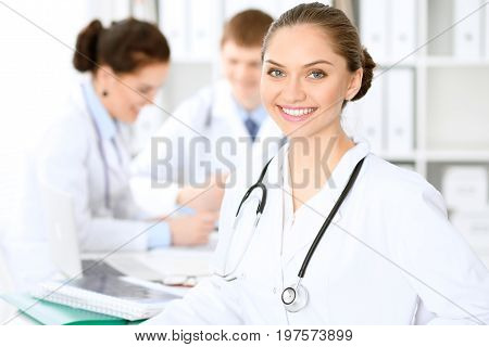 Happy doctor woman  with medical staff at the hospital sitting at the table and discussing medical history
