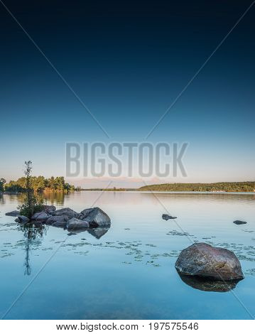 Granite rocks dot the still waters of Lower Buckhorn Lake at sunset.