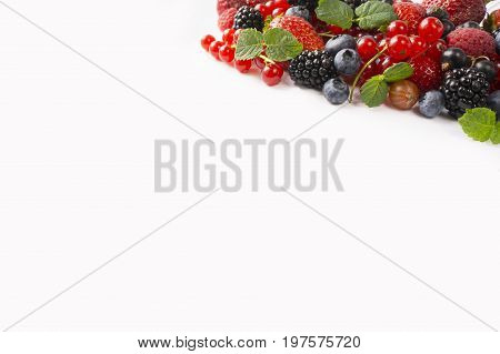 Ripe strawberries blueberries raspberries blackcurrants and red currants mint. Berries at border of image with copy space for text. Background berries. Top view. Various fresh summer berries on white background.