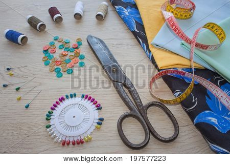 scissors and sewing kit includes threads of different colors thimble and other sewing accessories on wooden table. tools for sewing for hobby