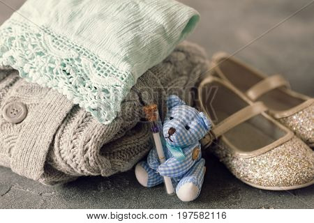 Stack Of Baby Girl Clothes And Shiny Shoes With Teddy Bea
