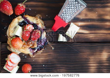 Blueberry cake decprated with fresh strawberry and white chocolate on the wooden background copy space