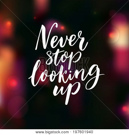 Never stop looking up. Motivational saying, brush lettering on dark background with pink bokeh