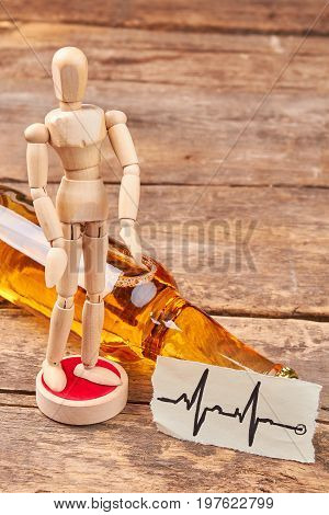 Wooden man figure, heart impulses. Wooden human dummy, bottle of alcohol, image of heartbeats.