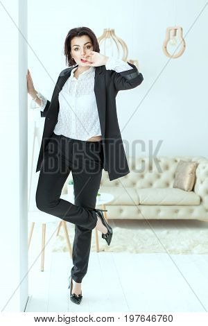 Charismatic woman dances near the wall. She is dressed in a business suit.
