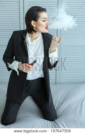 Cute woman smoking e-cigarette with smoke in the room.